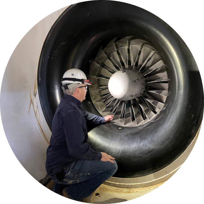 A peaking plant operator kneeling next to a turbine